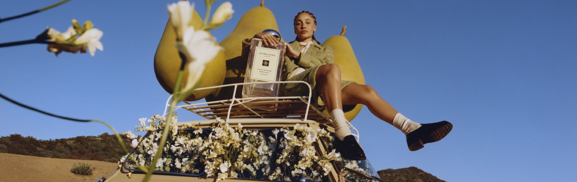 Global Ambassador for Jo Malone London, Adwoa Aboah stands on a ladder with a hot air balloon behind them