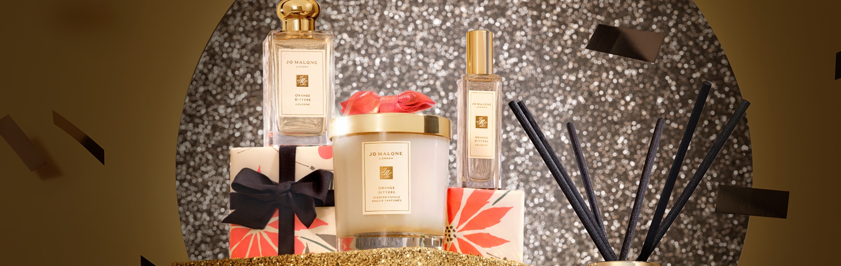 Jo Malone London Orange Bitters Collection Candle Cologne with gold lids on glittering gold plinths